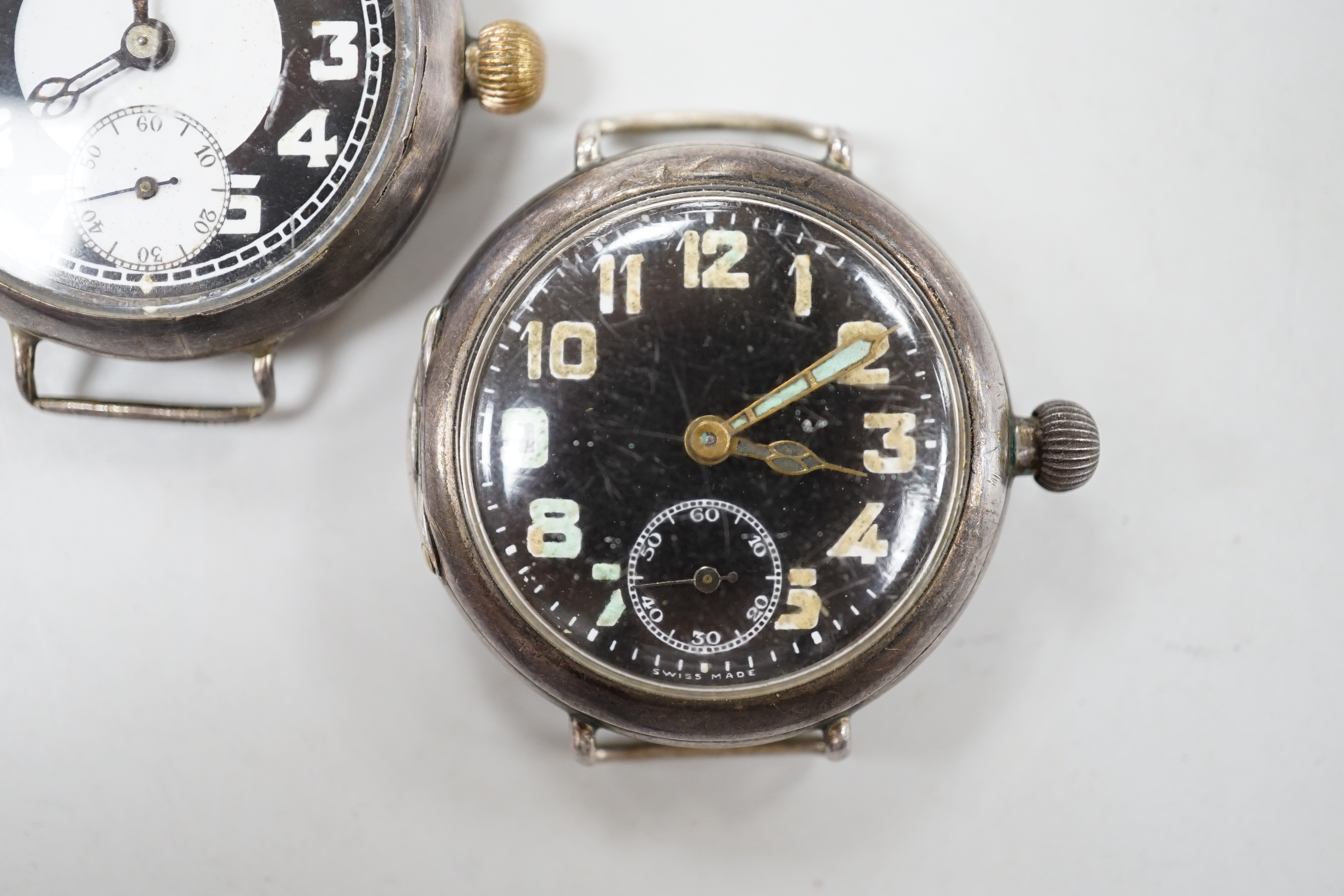 Two early 20th century silver manual wind wrist watches including black dial, both with subsidiary seconds, no straps.